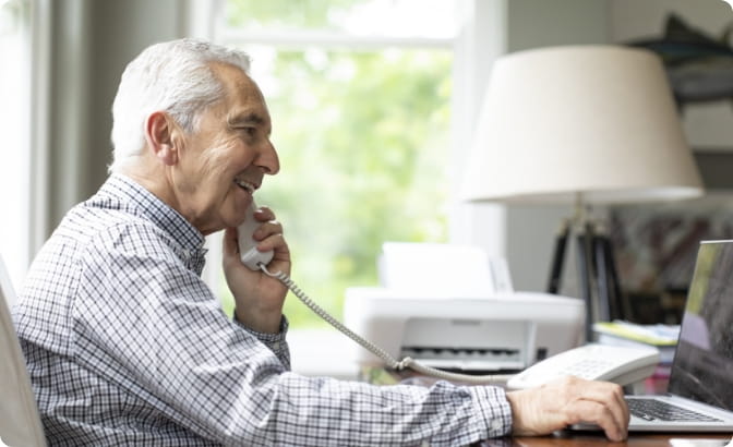 A man smiling and talking on the phone. 