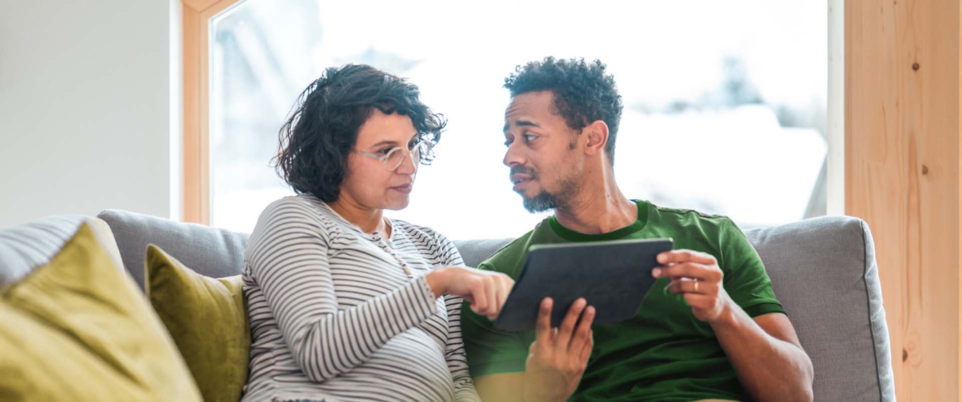 A couple use their tablet to research internet options and discuss the advancements of fiber-optic internet compared to DSL.