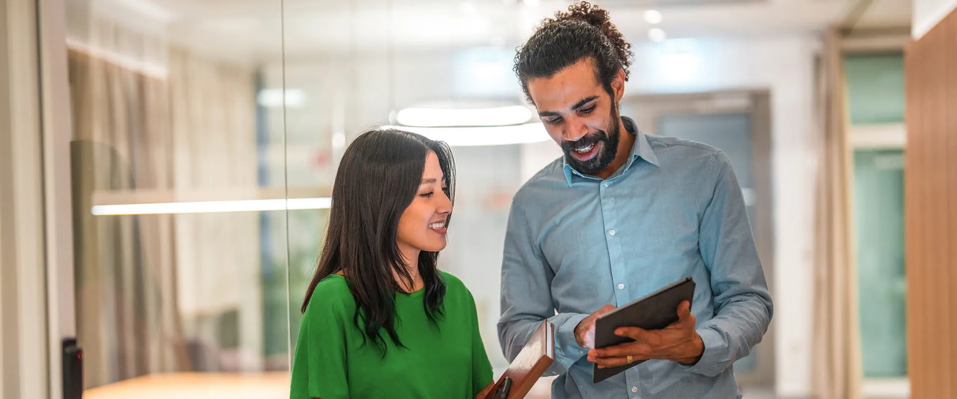 Pair of professionals review a report about quarterly metrics on a tablet connected to fiber-optic internet. 