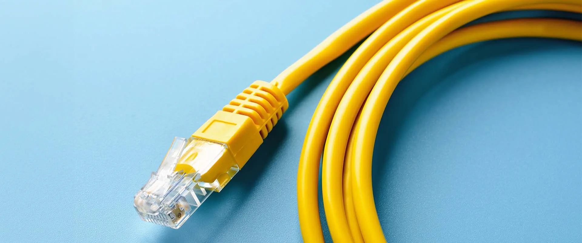Close-up photo of a yellow ethernet cable used to connect computers and gaming consoles to a router or gateway 