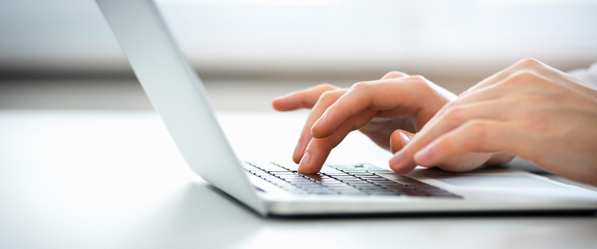 Pair of hands poised over a laptop keyboard 