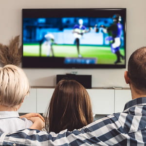 Over the shoulder view of family on a couch live-streaming sports on fast fiber internet  