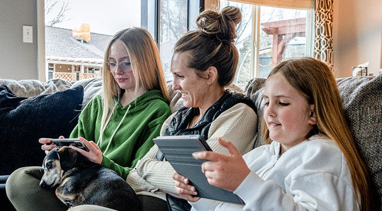 Family hangs out on the couch with multiple tablets connected to their discounted internet. 