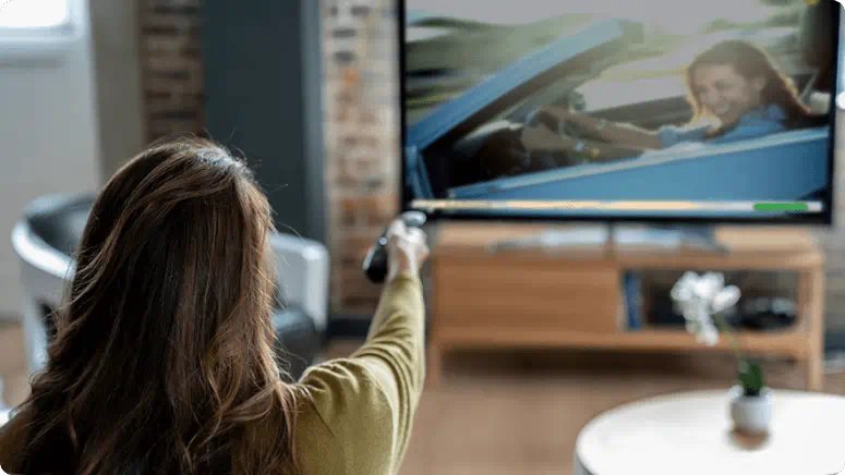 Person pointing remote at a smart TV streaming classic movie content 