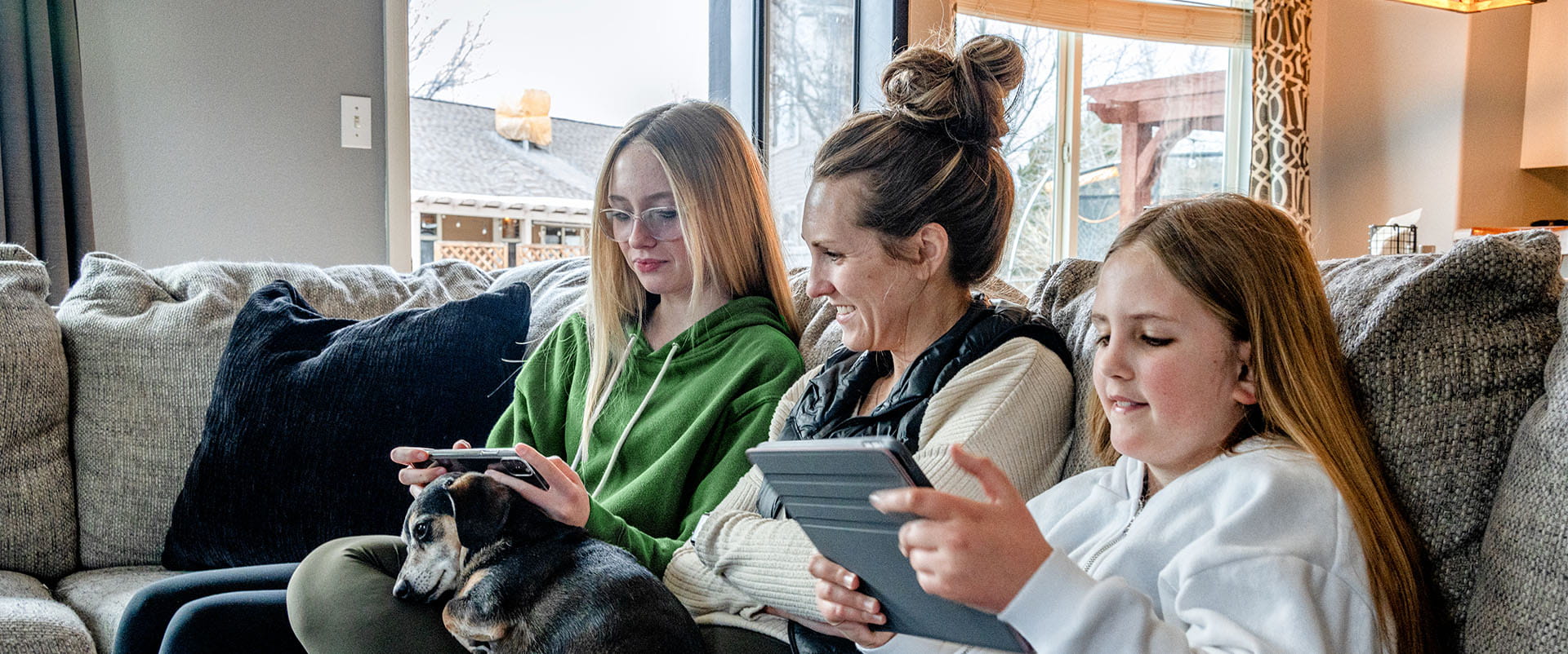 Family hanging out on the couch with dog and devices while enjoying fast affordable internet 