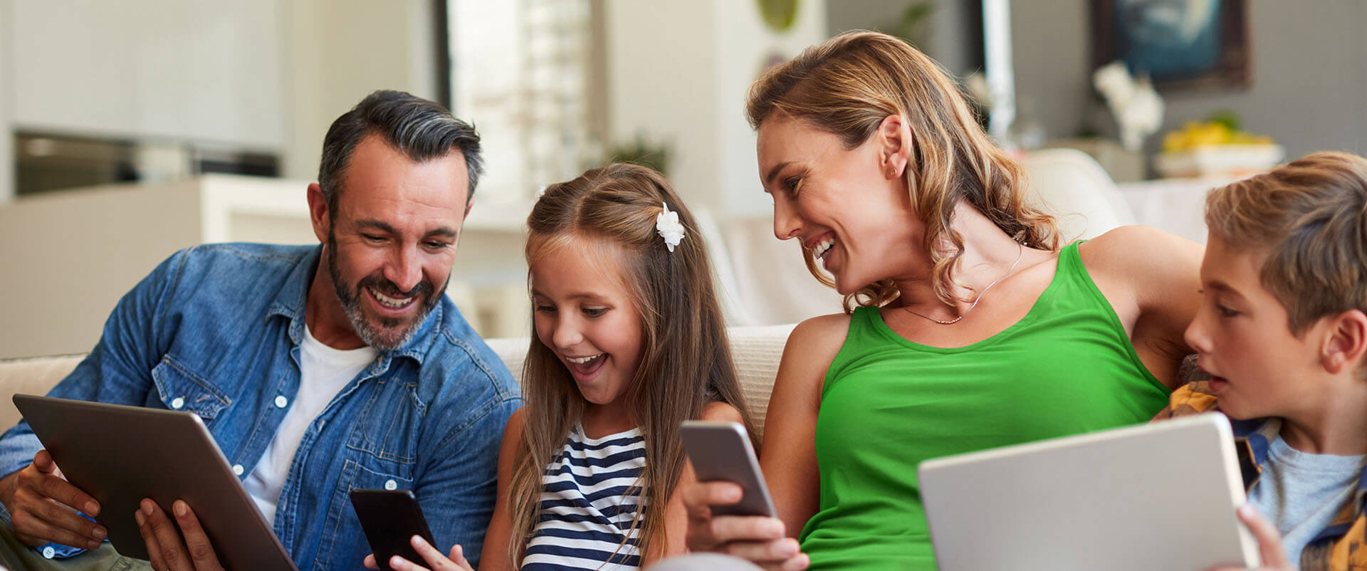 Family of four laughing at content streaming over their gig-speed WiFi. 