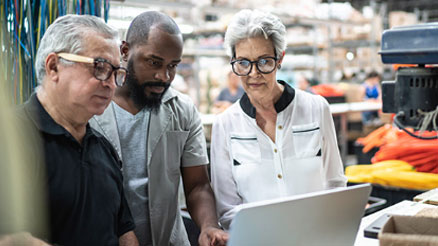 Three people looking at a laptop