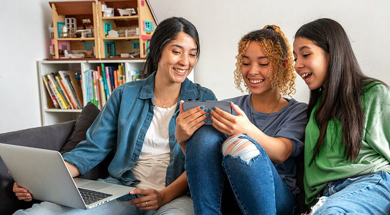 A group of students use fast fiber internet to stream content over a laptop and smartphone 