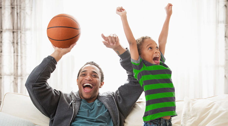 Father and son celebrate with their favorite basketball team as they stream the big game over fast, fiber internet. 